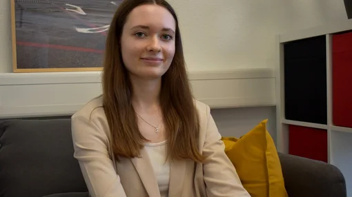 Studienzweifellos Erfahrungsberichte Sophia Eine junge Frau sitzt auf einem Sofa in einem Büro- oder Beratungsraum und blickt ruhig in die Kamera.